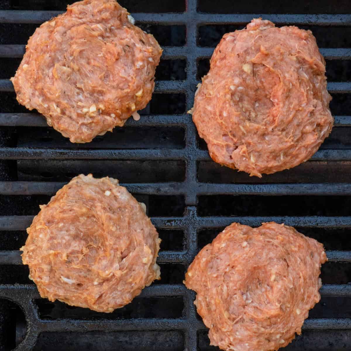 Turkey burgers on grill before grilled.