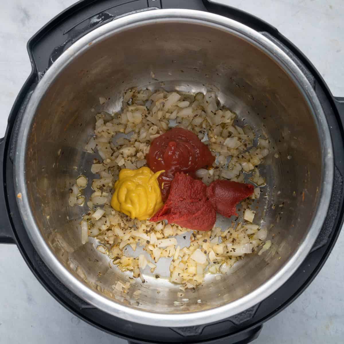 Beans removed from pressure cooker pot with cooked onions, tomato paste and ketchup and mustard added.