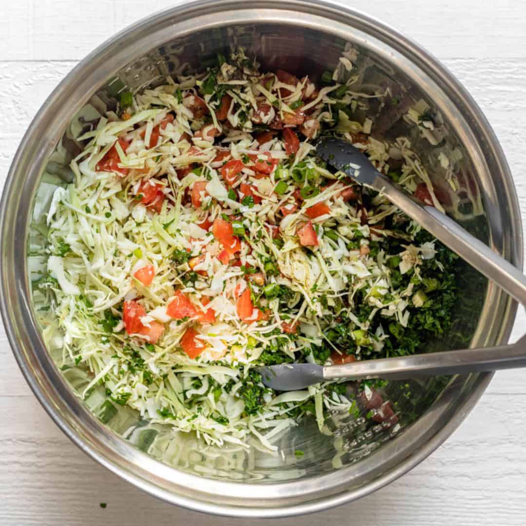 Slaw after tossing with tongs dipped in bowl.
