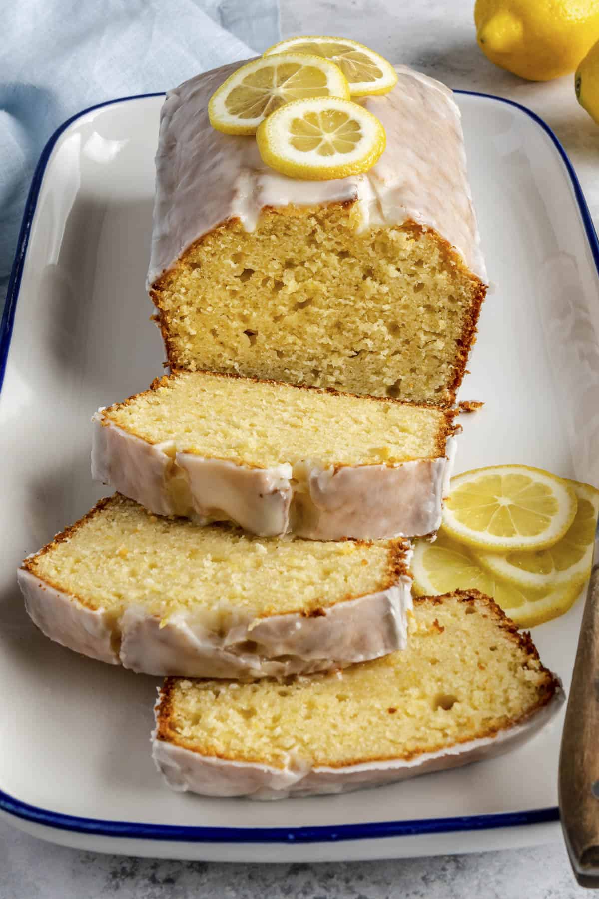 Homemade lemon bread on a platter with a few slices cut and laying forward to show inside texture.