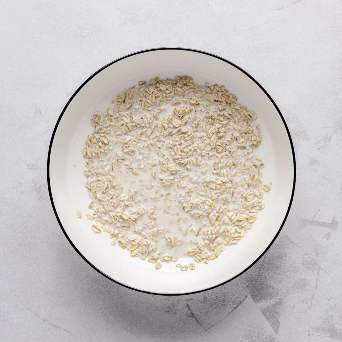 Hot milk in a medium bowl with oats added.