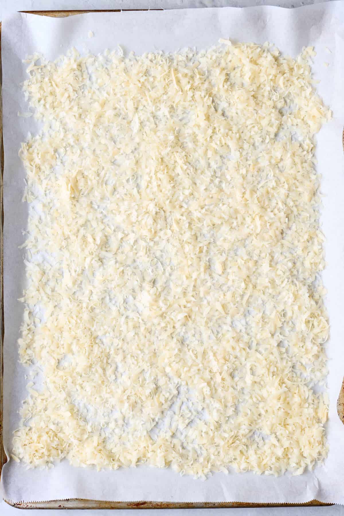 Grated cheese spread evenly on a parchment lined baking sheet.