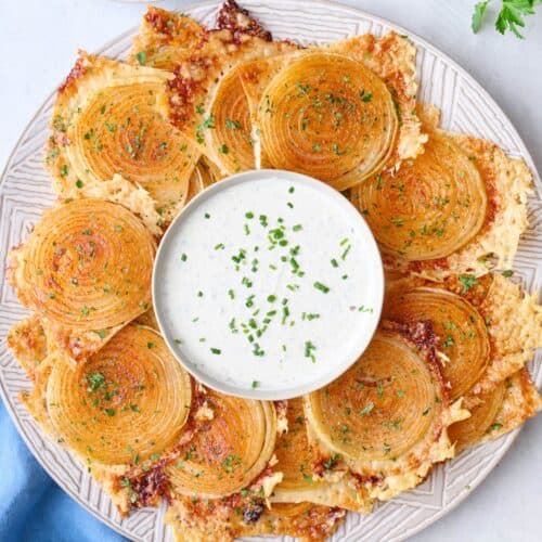 Onion ring chips on a platter with a small dish of ranch in the center.