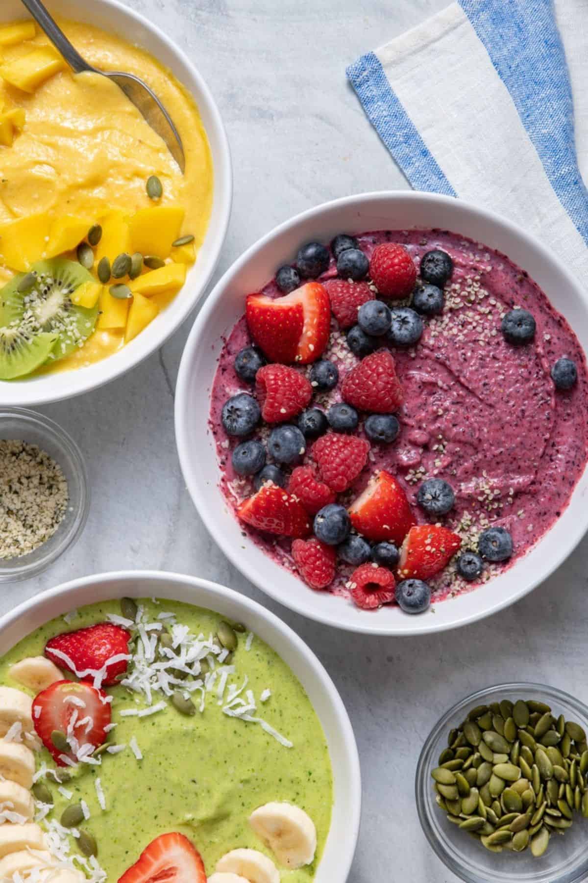 Smoothie bowls 3 ways: strawberry blueberry, mango banana, and green machine.