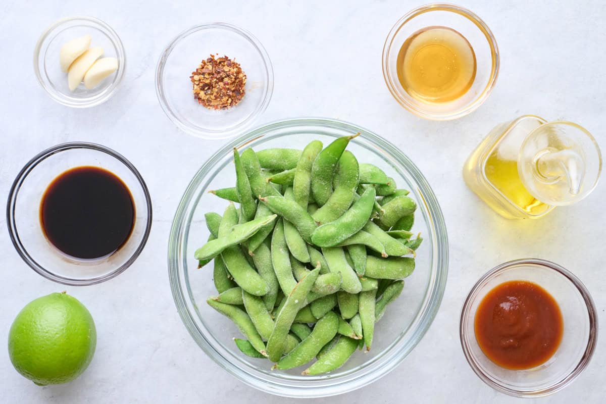 Ingredients for recipe: frozen edamame pods, garlic, soy sauce, lime, red pepper flakes, honey, oil and sriracha.