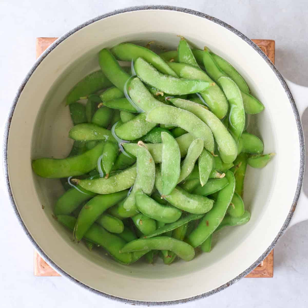 Frozen edamame in a pot of water.