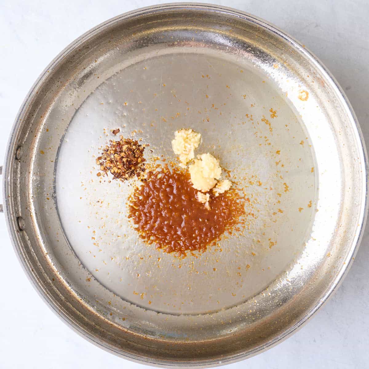 Garlic, sriracha and red pepper flakes in hot oiled skillet.