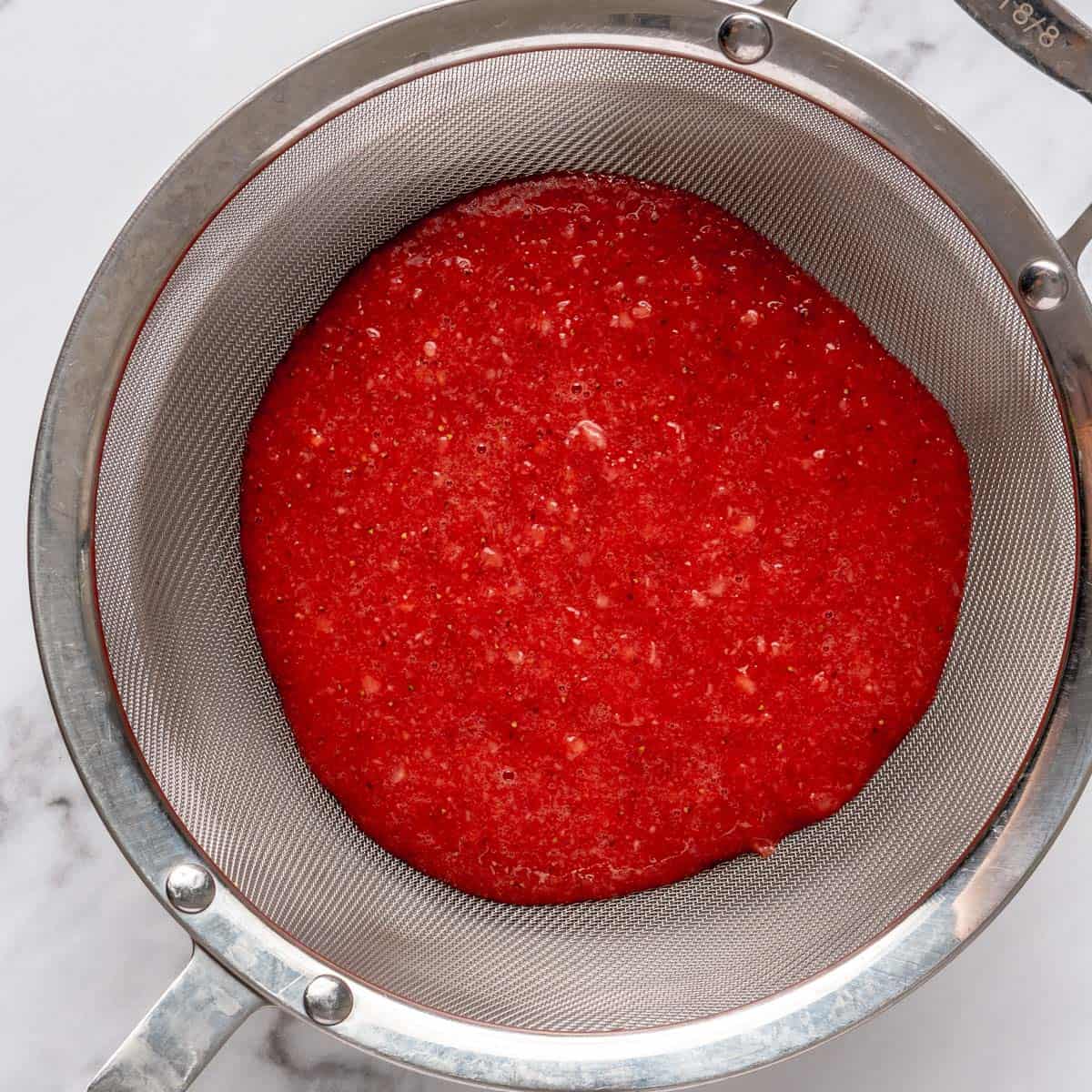 Blended strawberries in a fine mesh sieve.