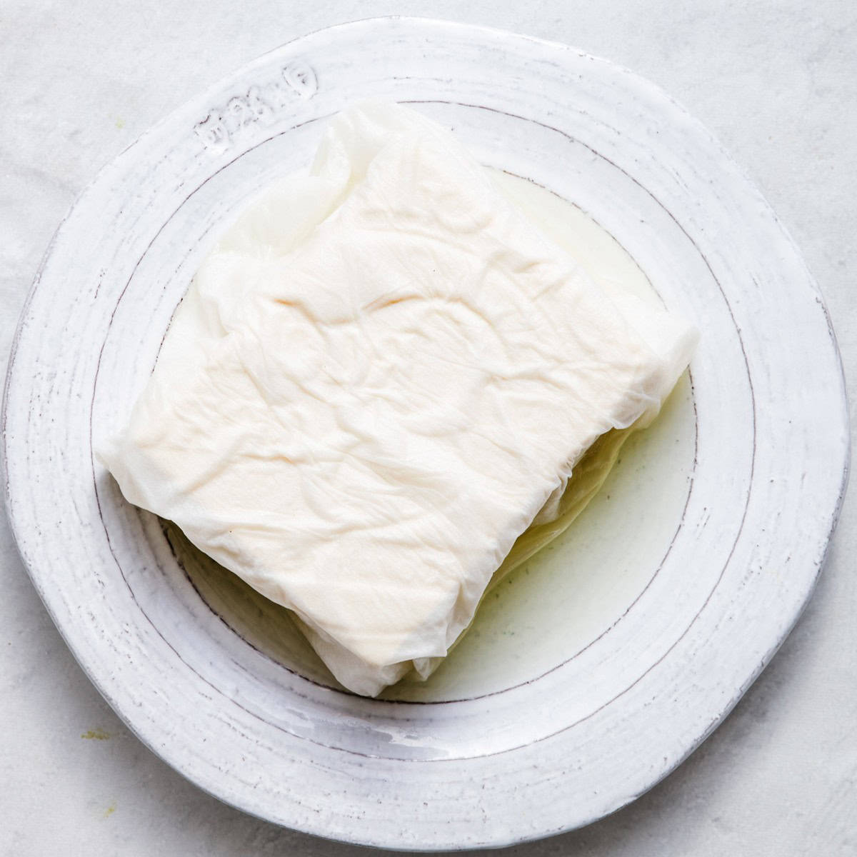 Tofu after 30 minutes, showing its liquid in the plate.