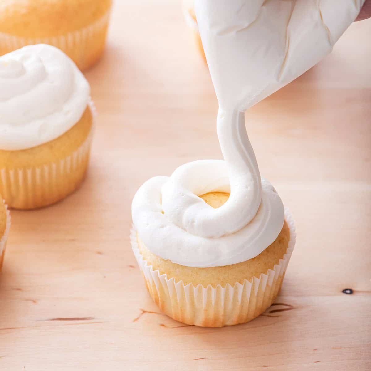 Topping cupcakes with homemade cream cheese frosting.