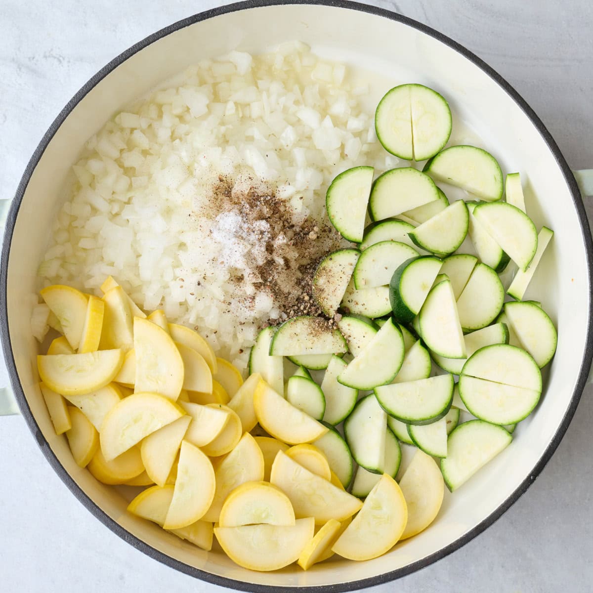 Chopped veggies in a pot with seasonings before cooking. 