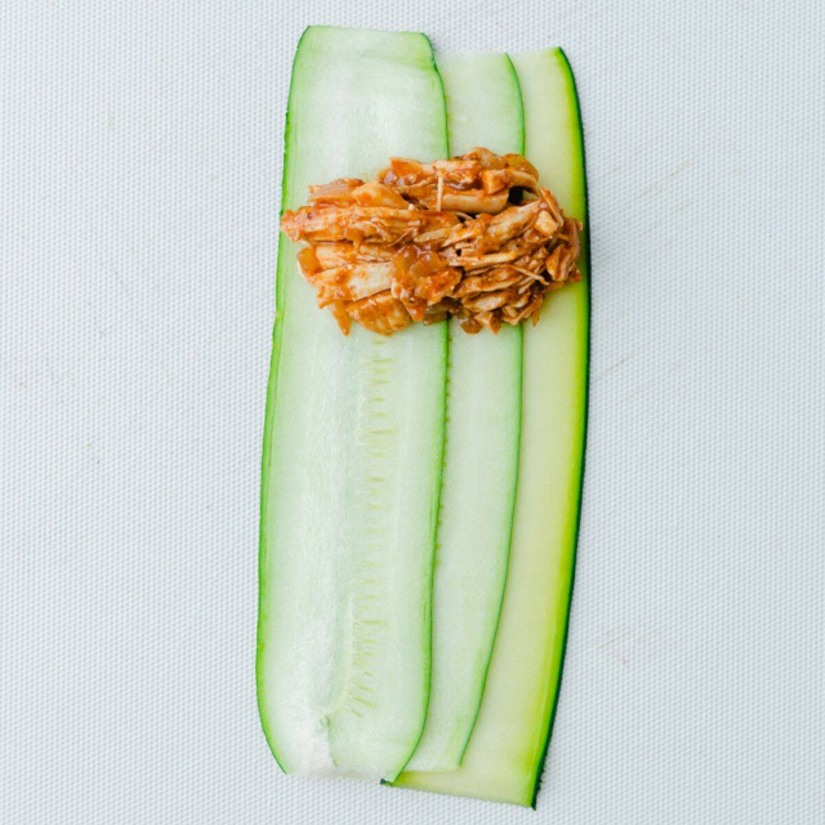 3 zucchini planks on a surface with filling added on towards top.