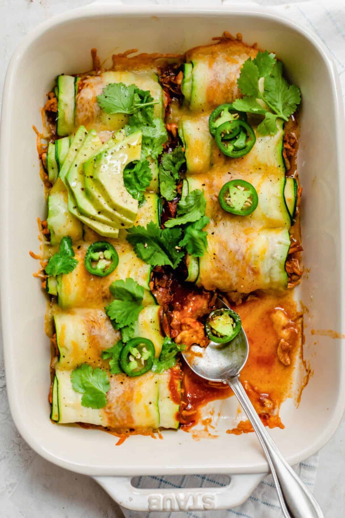 Zucchini enchilada recipe topped with avocado and jalapeno slices.