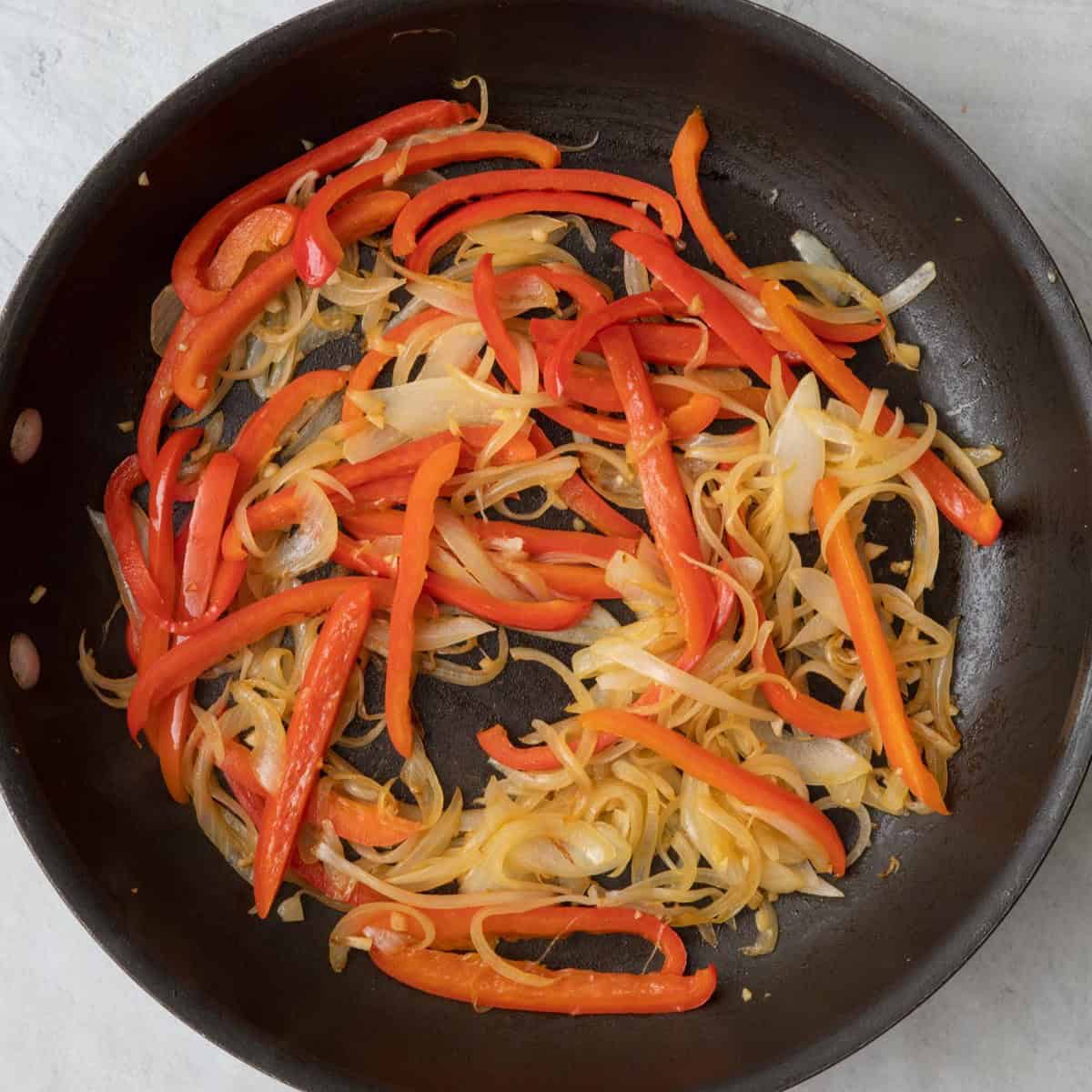 Onions, peppers, and garlic cooked in skillet.