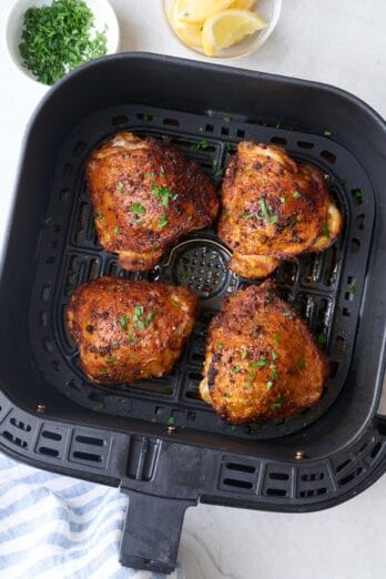 Easy air fried chicken thighs in an air fryer basket.