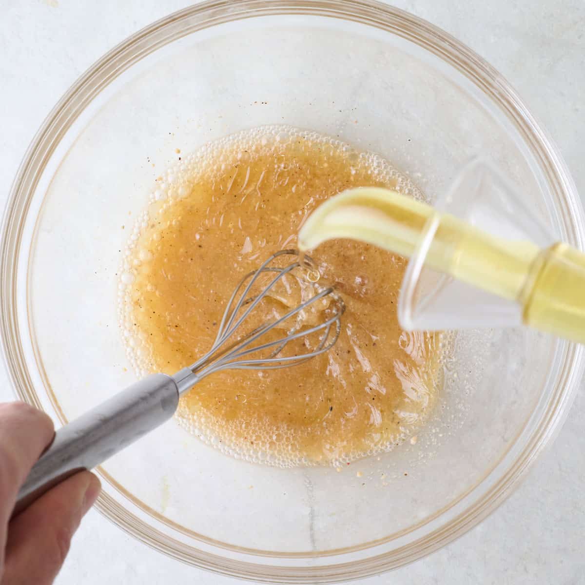 Whisking dressing while pouring in oil.