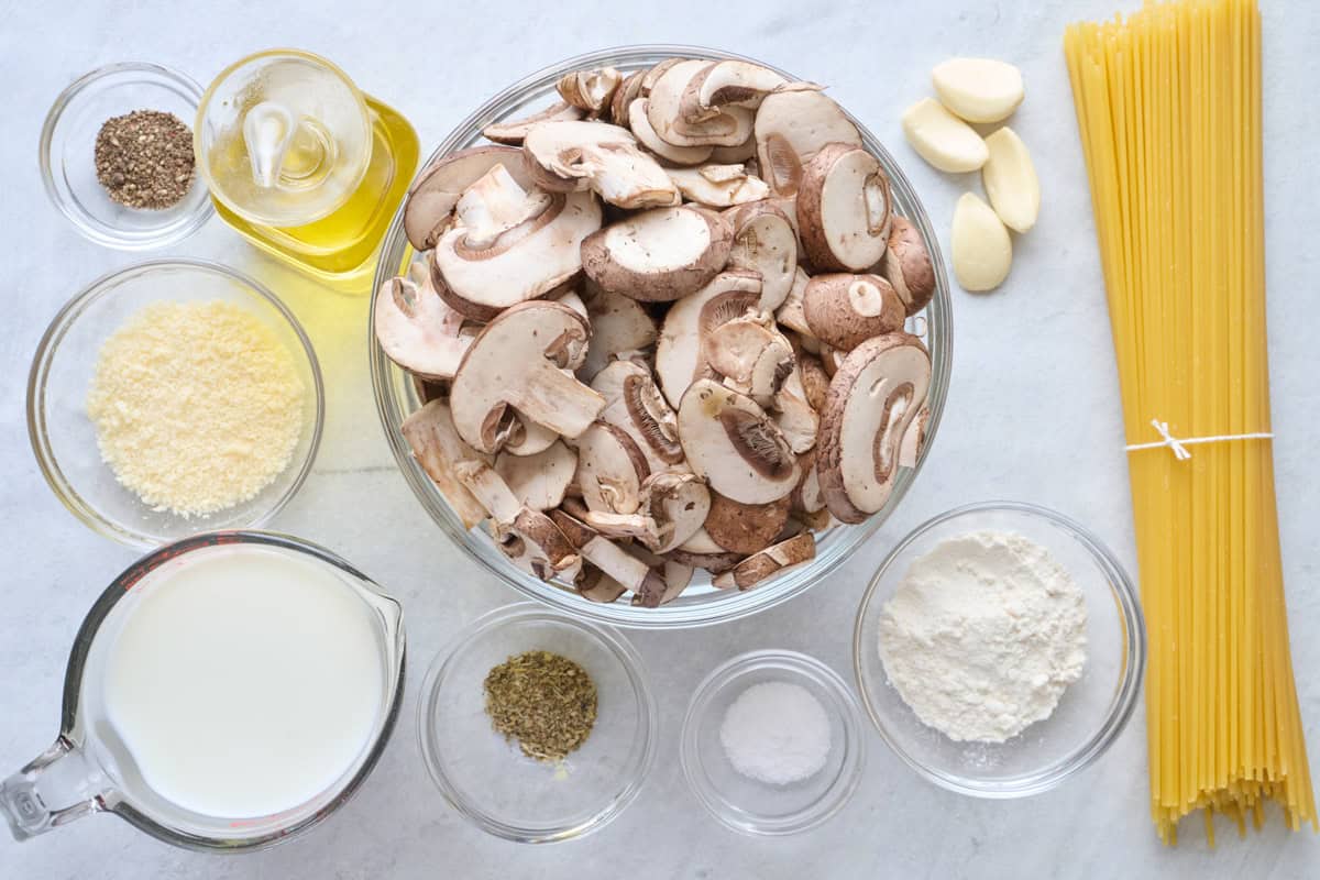 Ingredients for recipe: sliced mushrooms, black pepper, oil, parmesan, milk, italian seasoning, salt, flour, garlic cloves and dry pasta.