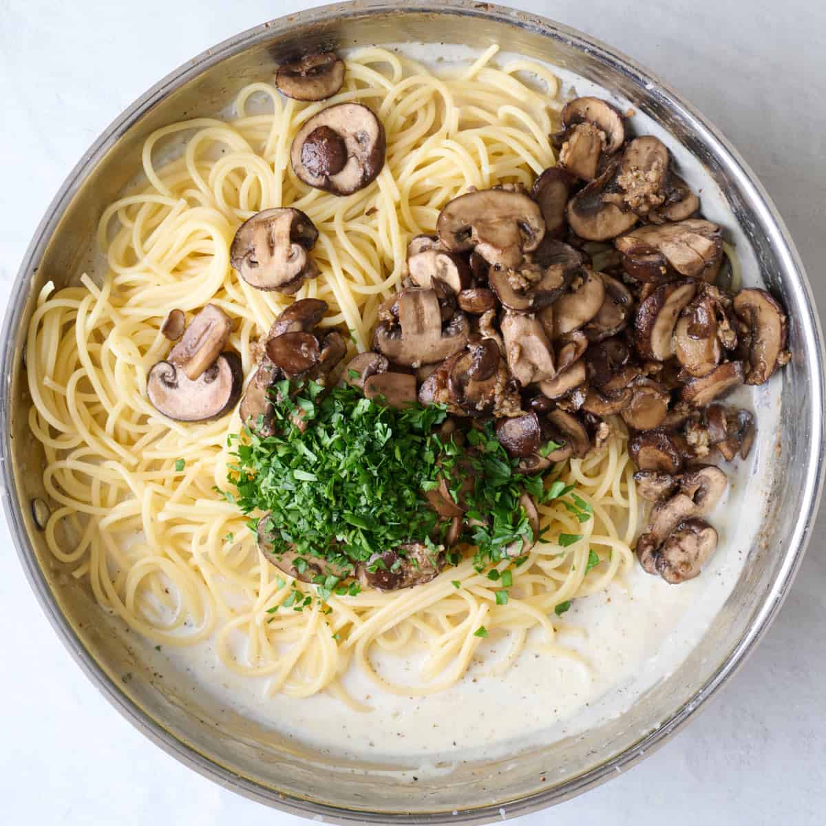 Sauce after thickening with pasta, mushrooms, parsley, and pasta water added.