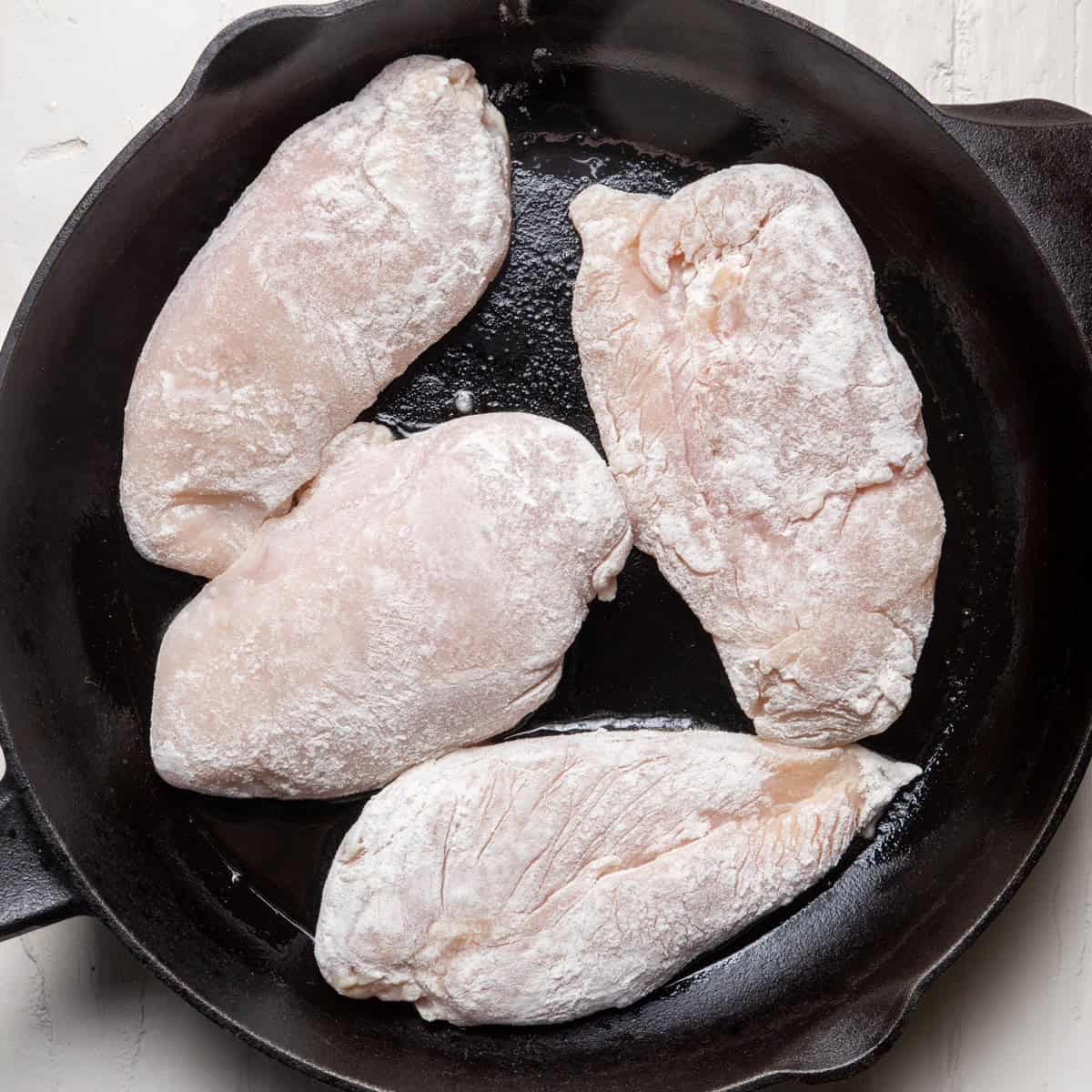 Dredged chicken breast in an oiled cast iron skillet.