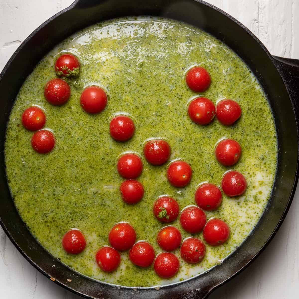 Pesto, broth, milk, and tomatoes added to skillet.