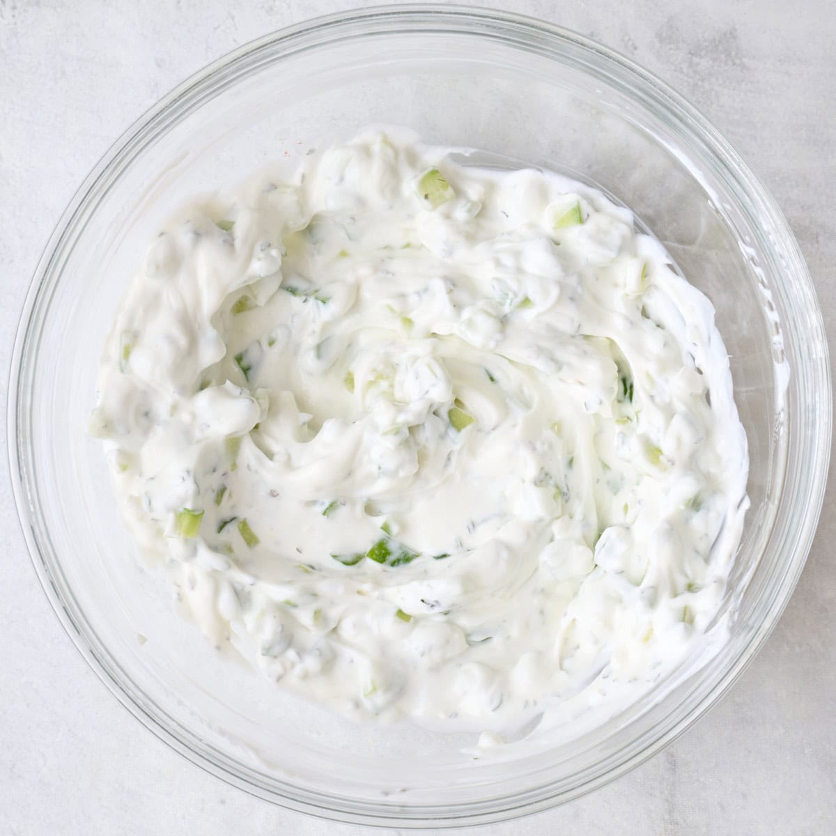 Creamy yogurt sauce with cucumber after mixing.
