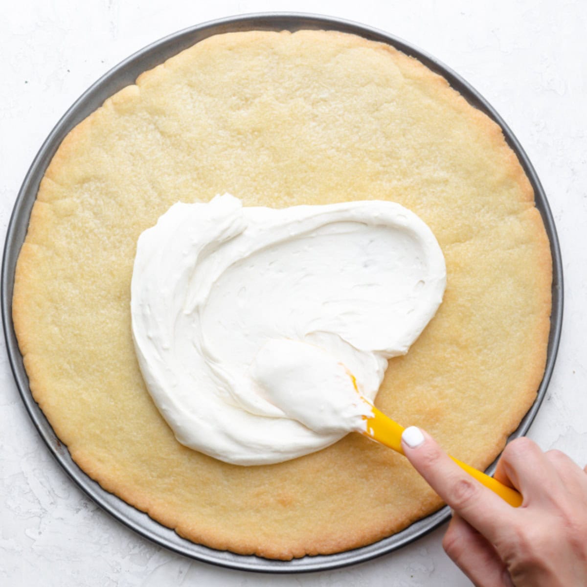 Spreading cream over cookie.