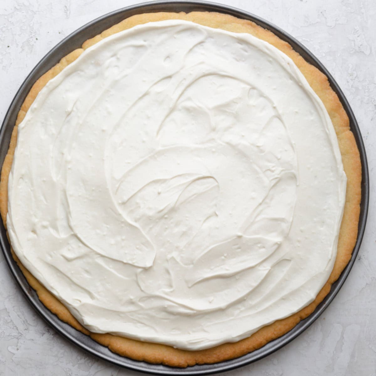 Sweet cream spread on top of cookie pizza.