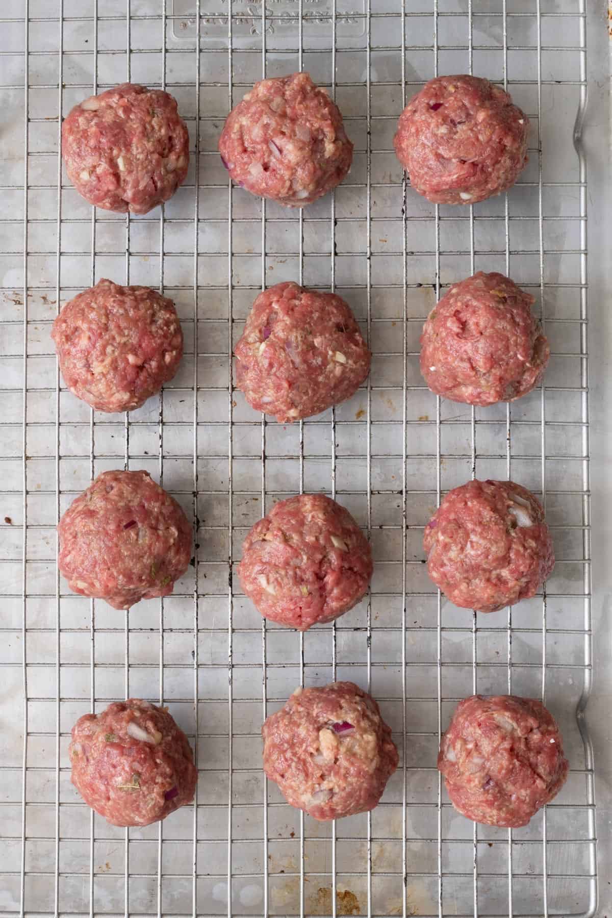 Meatballs rolled on a wire rack before baking.