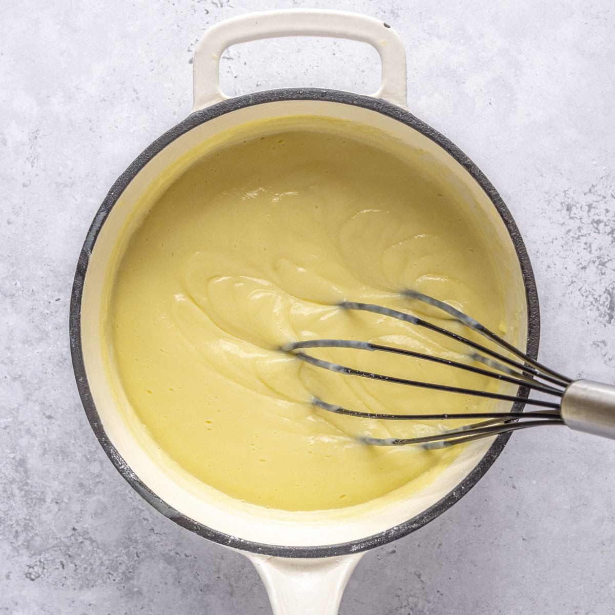 Whisking thickened pudding in pot.