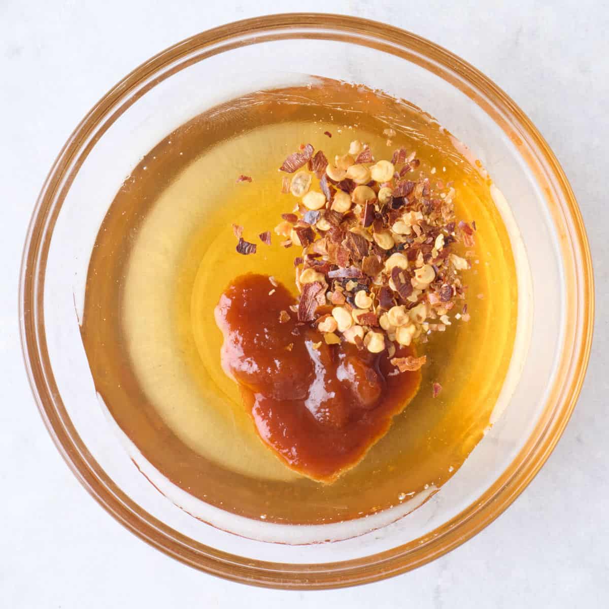 Warmed honey, sriracha and crushed red pepper in a small bowl.