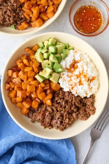 Viral hot honey ground beef bowls with seasoned beef, roasted sweet potatoes, diced avocado and hot honey drizzled on top.