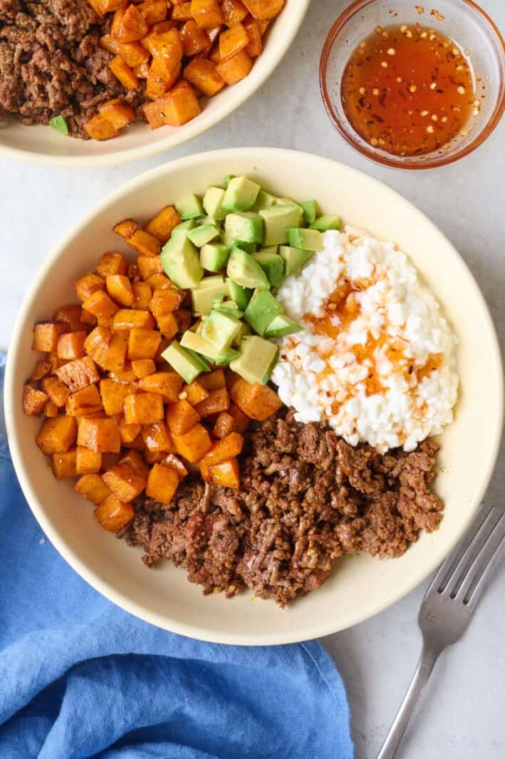 Viral hot honey ground beef bowls with seasoned beef, roasted sweet potatoes, diced avocado and hot honey drizzled on top.