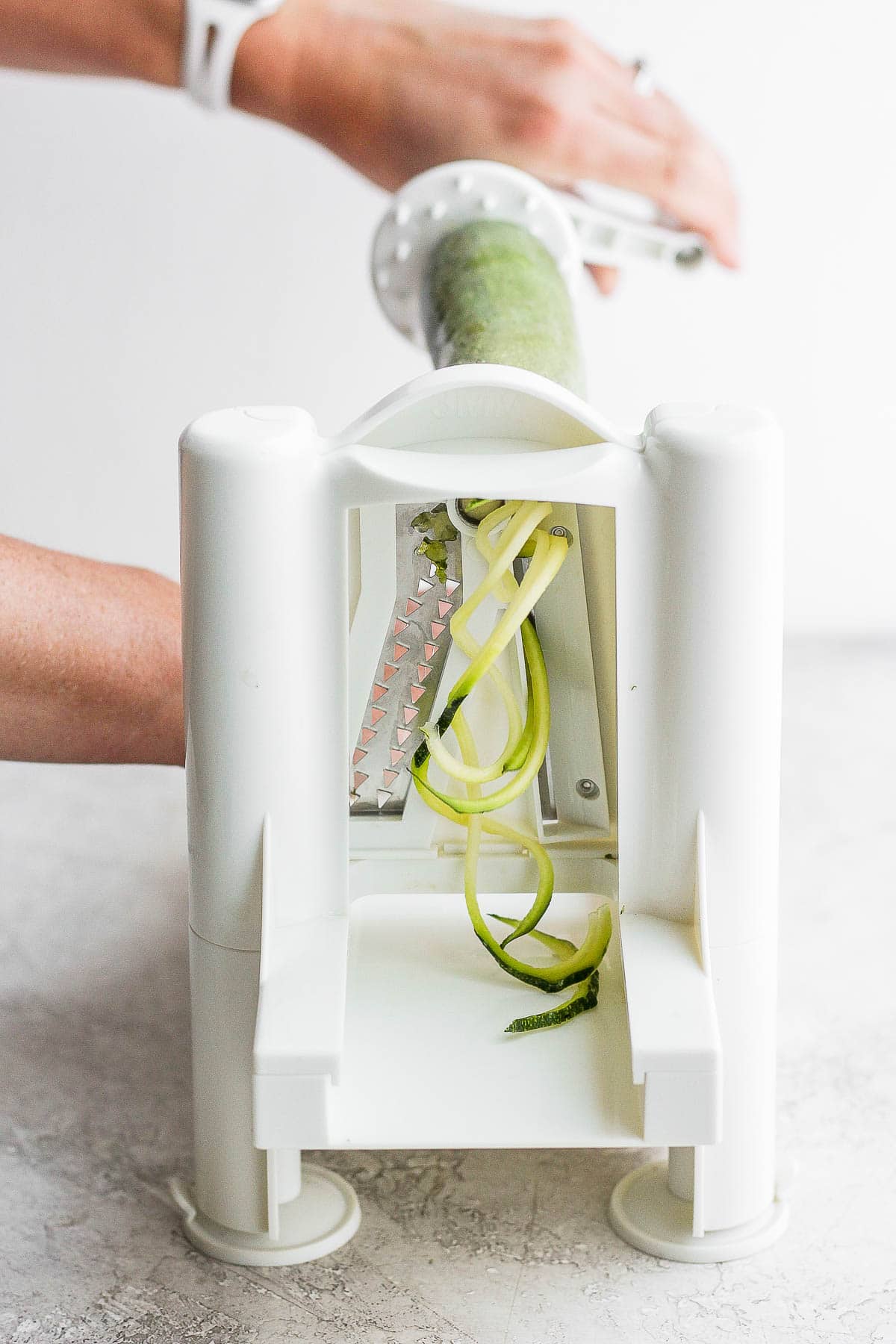 A spiralizer machine starts to cut a zucchini.
