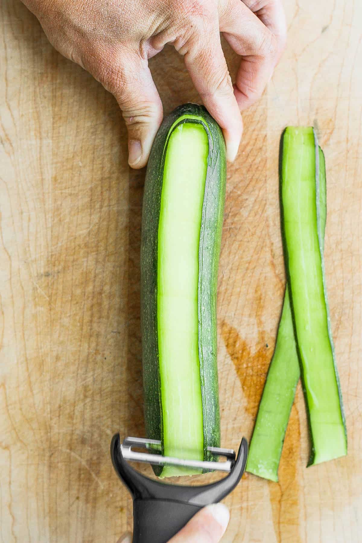 Y-peeler cutting thin planks of zucchini.