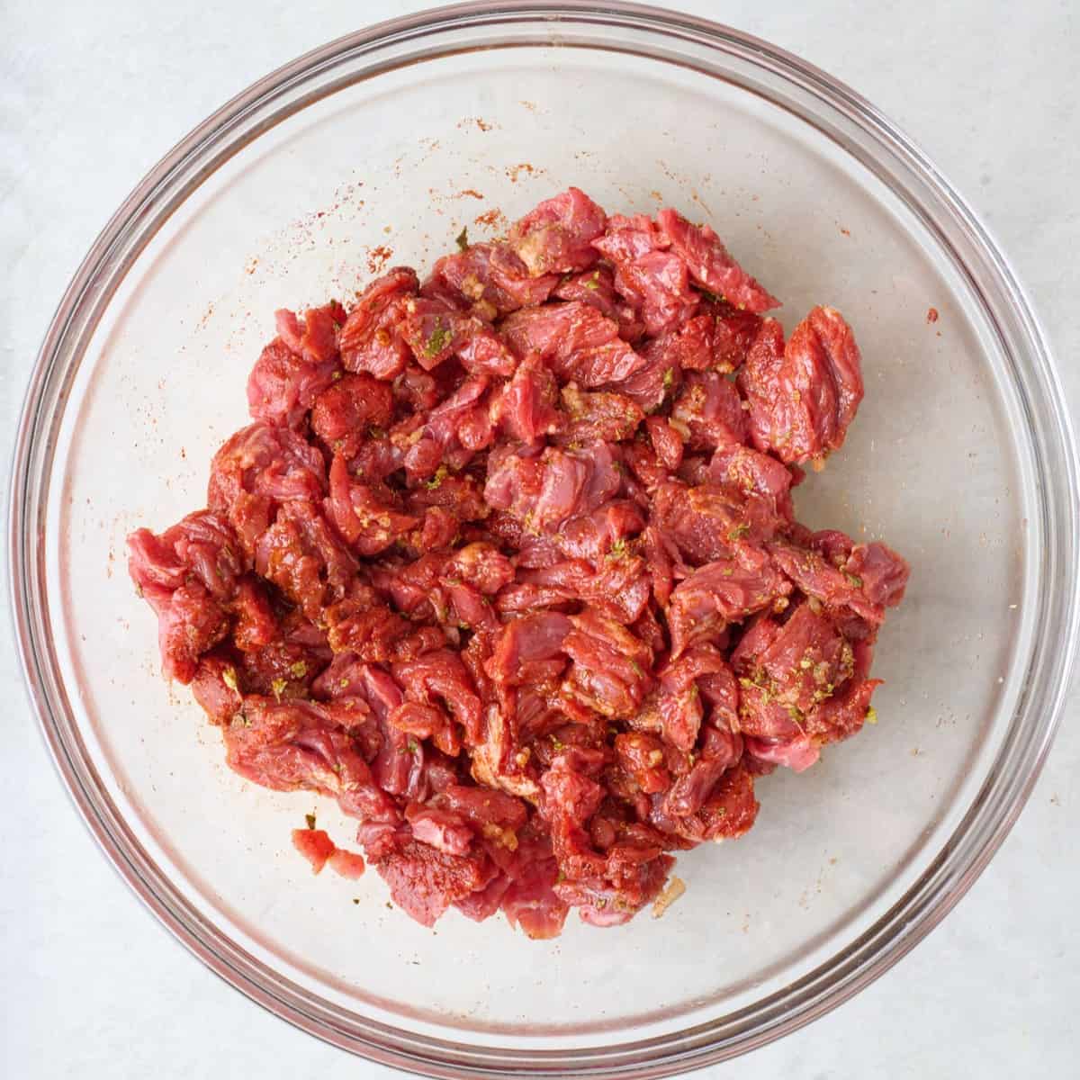 Beef pieces in a bowl coated in seasoning blend.