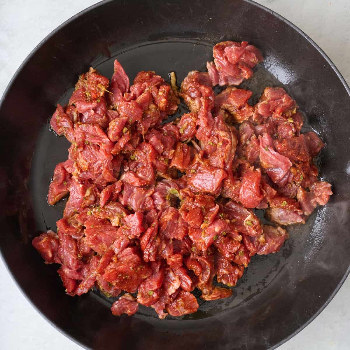 Seasoned beef added to skillet.