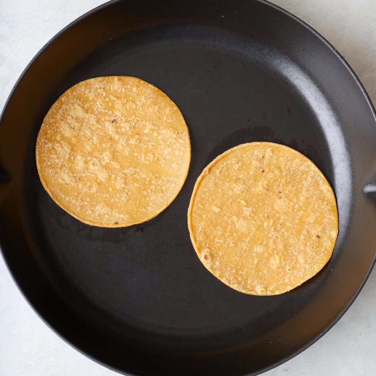 Corn tortilla shells after browning in a skillet.