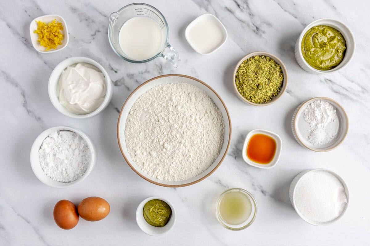 Ingredients for recipe: lemon zest, yogurt, milk, powdered sugar, eggs, pistachio butter, crushed pistachios, sugar, vanilla, lemon juice, baking powder and salt.