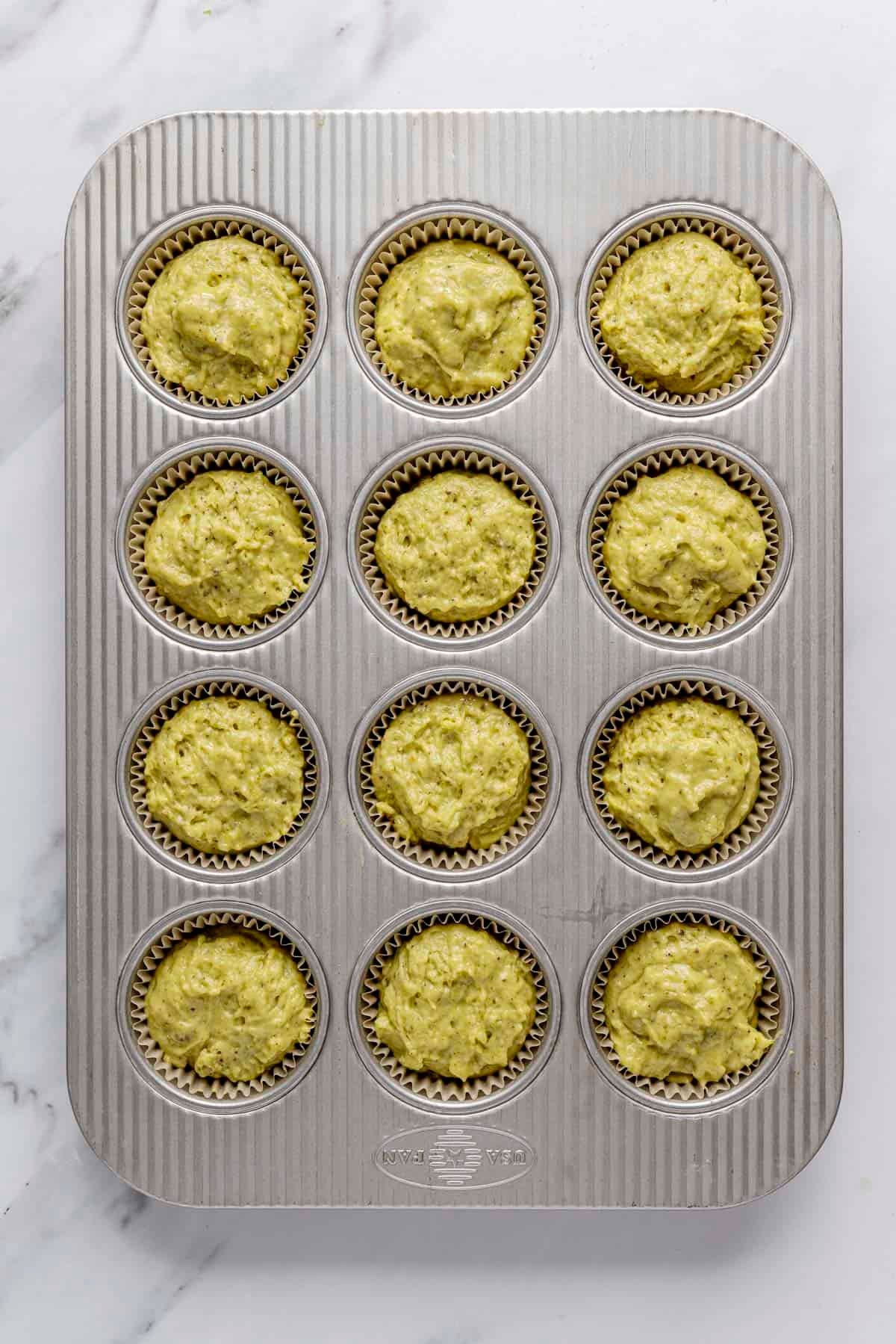 Muffins in parchment paper line muffin pan before baking.
