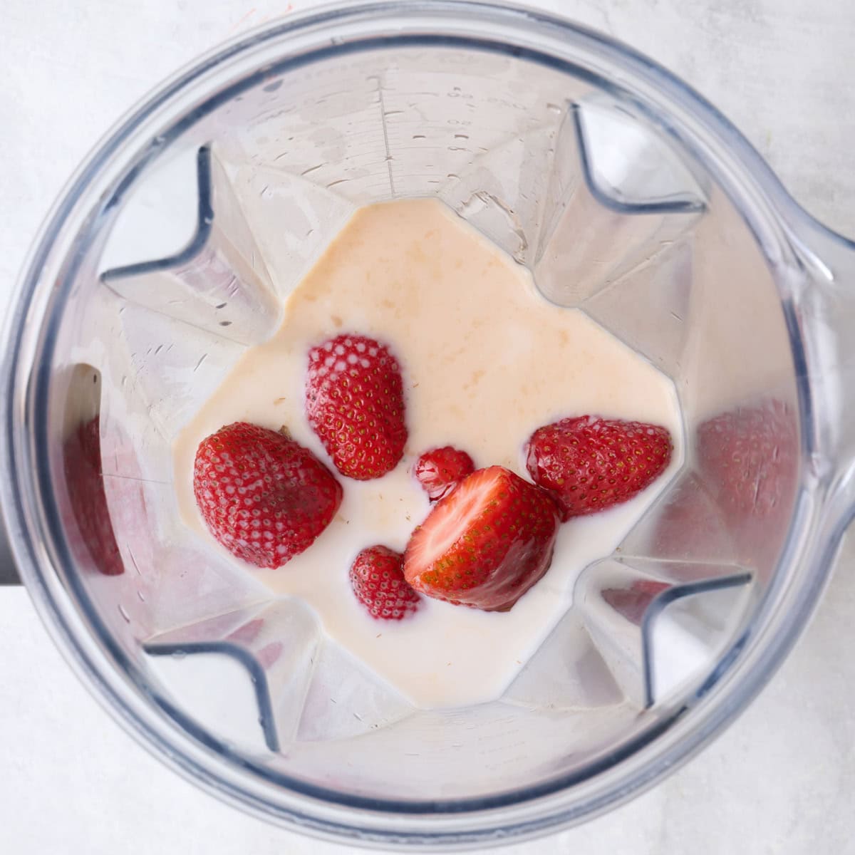 Milk, honey, vanilla and fresh strawberries in a blender.