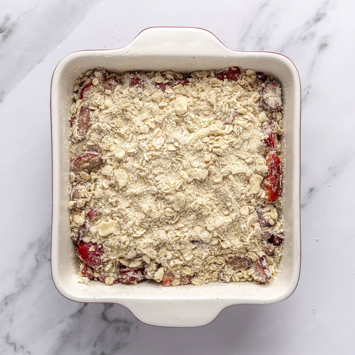 Streusel mixture sprinkled over fruit in dish.