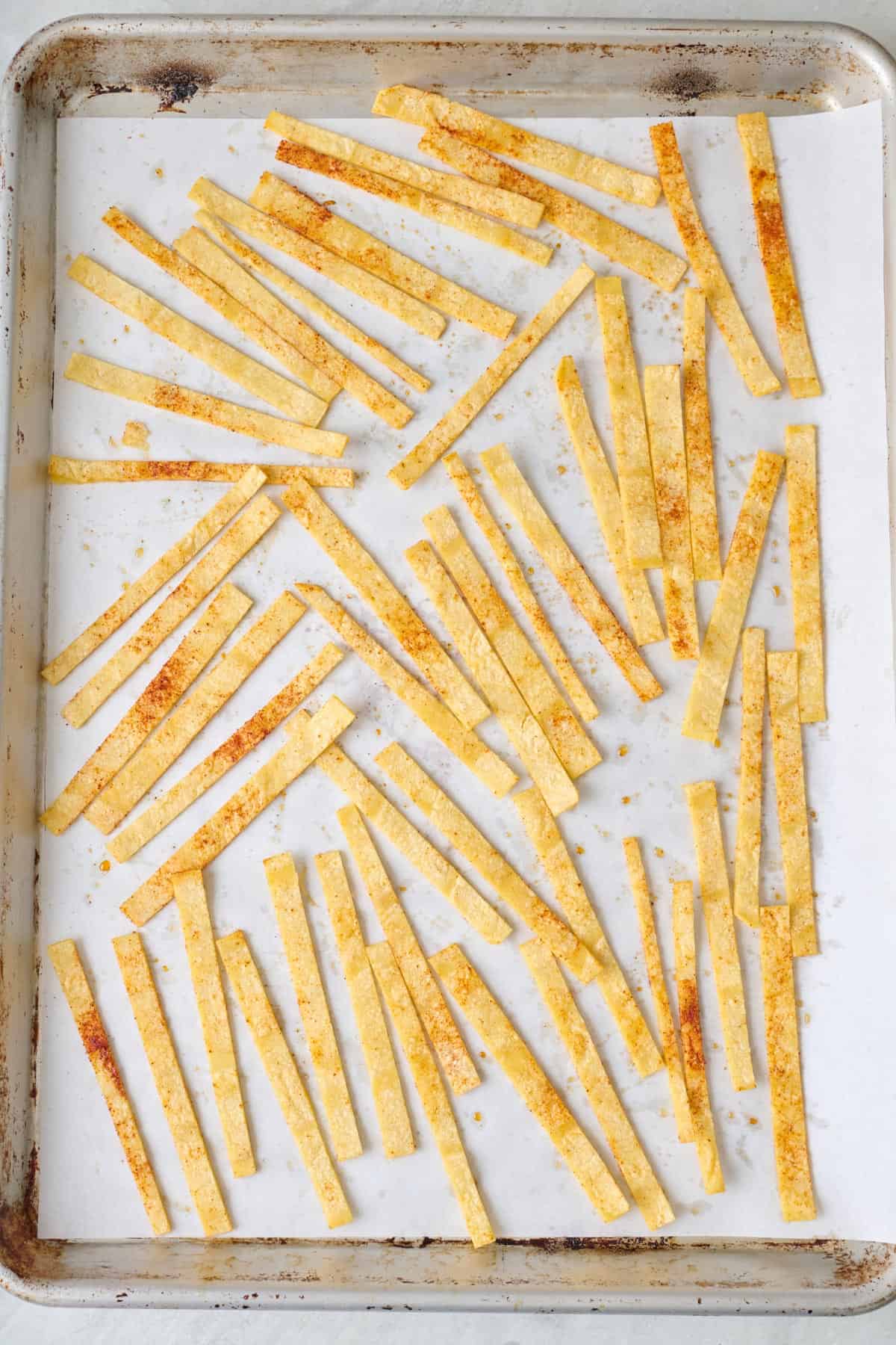 Seasoned tortilla strips on a baking sheet.
