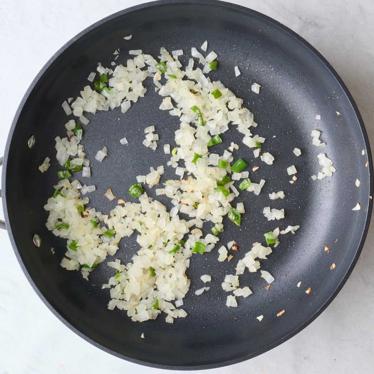 Onions and jalapeno peppers in a skillet after cooking.