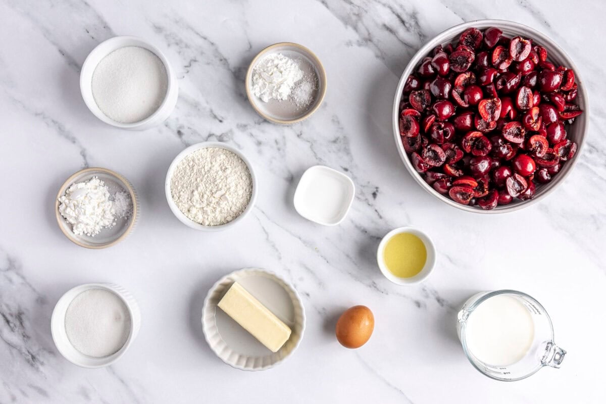 Ingredients for recipe in individual dishes: fresh cherries, flour, sugar, cornstarch, lemon juice, extract, baking powder, egg and milk.
