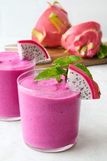 Two glasses of dragon fruit smoothie with a small wedge of fresh dragon fruit on each glass.