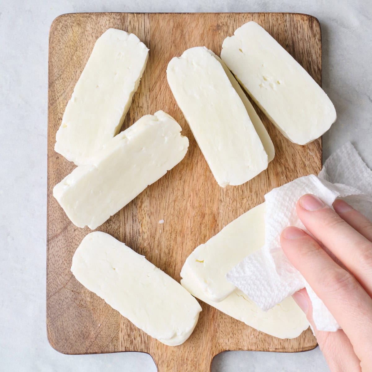 Paper towels patting the cheese slices dry.