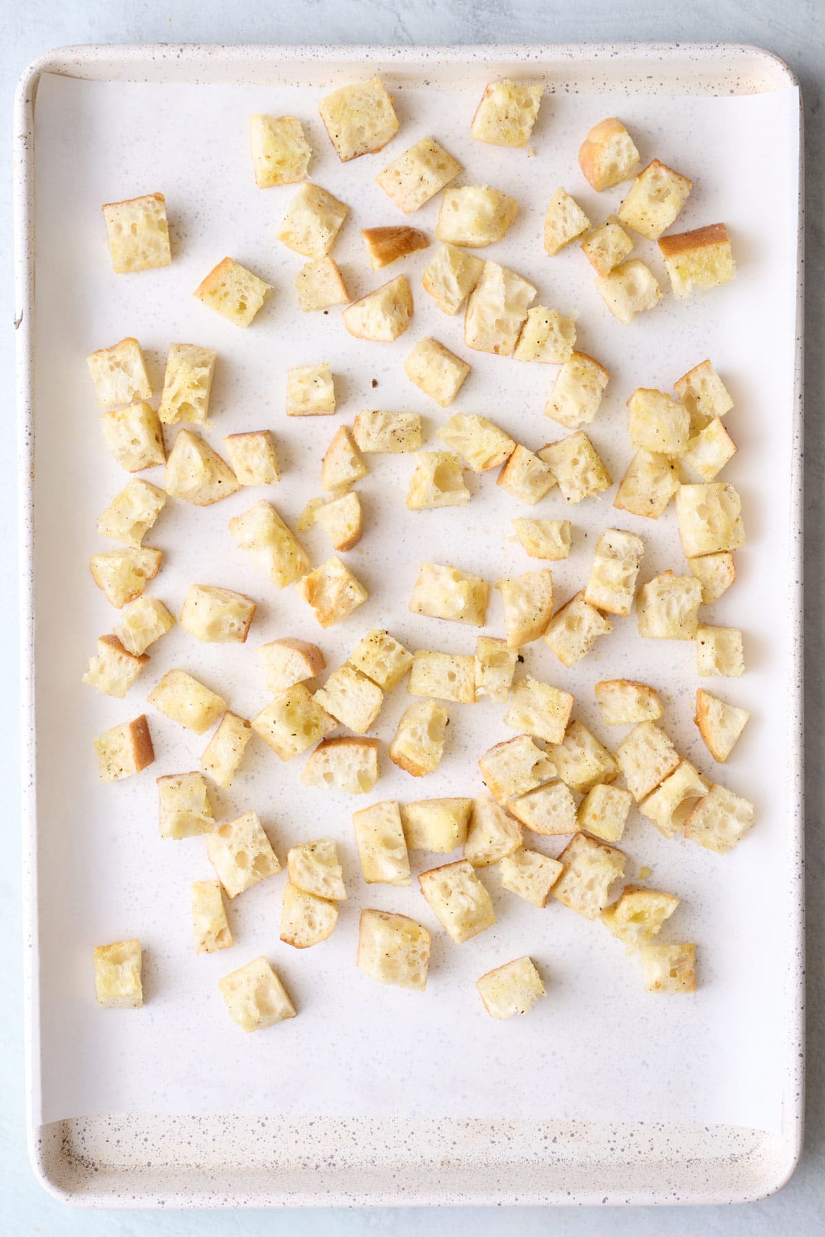 Bread cubes on a small sheet pan tossed with oil, sat and pepper.
