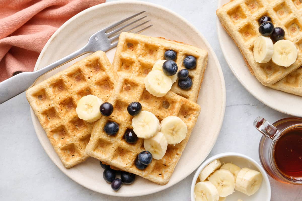 Easy oatmeal waffles on a plate with fresh blueberries and sliced bananas on top.