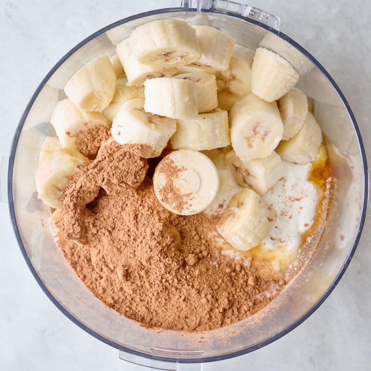 Frozen bananas, yogurt, chocolate protein powder, honey and cocoa powder in a food processor.