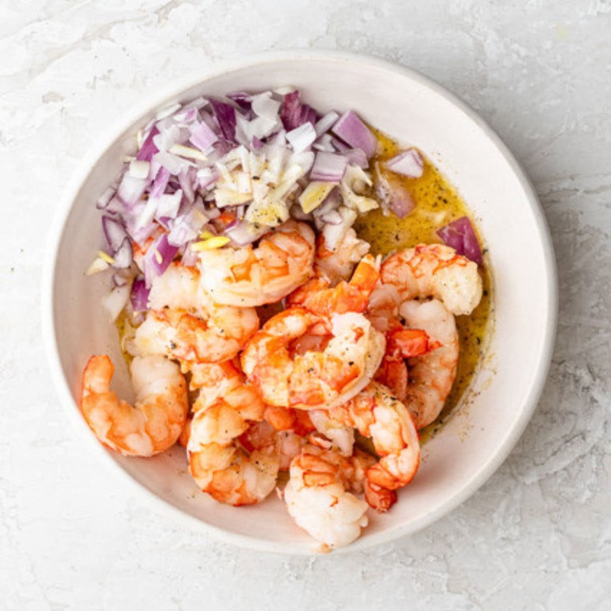 Shrimp, onions and dressing in a bowl.